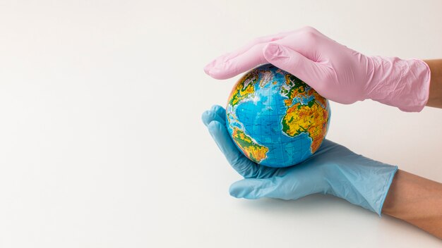 Hoher Handwinkel mit Handschuhen, die Globus mit Kopierraum halten