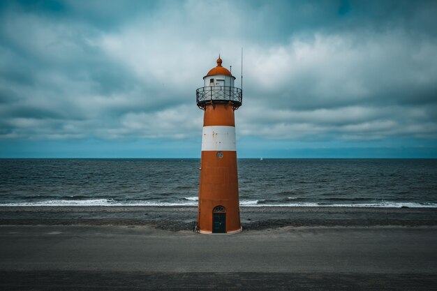 Hoher Leuchtturm an der Nordsee bei bewölktem Himmel