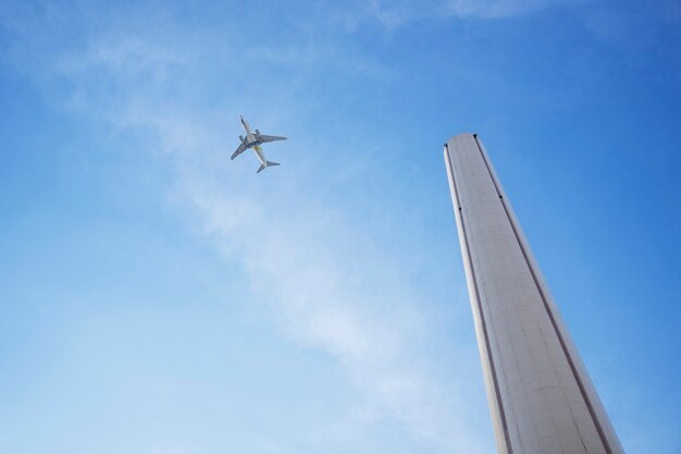 Hoher Schornstein und Flugzeug mit niedrigem Winkel