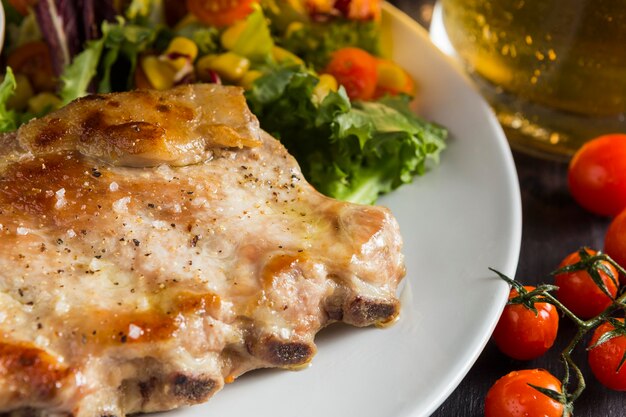 Hoher Steakwinkel auf Teller mit Bier