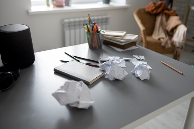 Hoher unordentlicher Schreibtisch mit zerknittertem Papier