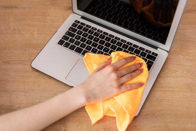 Hoher Winkel der Frau, die Laptop mit Stoff reinigt