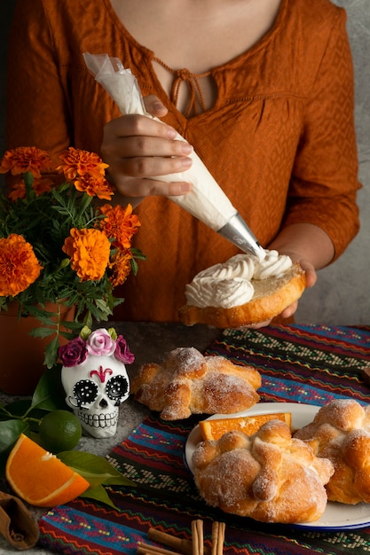 Hoher Winkel der Frau, die pan de muerto mit Sahne verziert