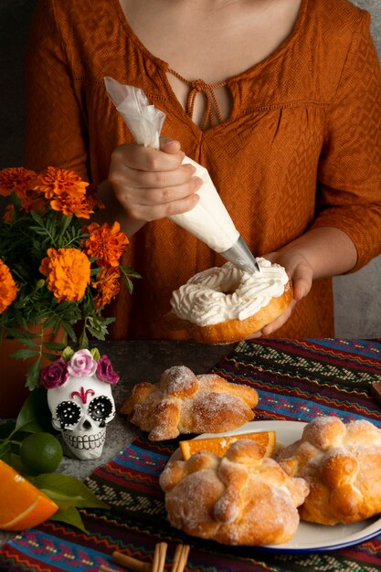 Hoher Winkel der Frau, die pan de muerto mit Sahne verziert