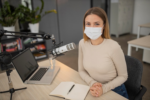 Hoher Winkel der Frau mit medizinischer Maske im Radiostudio