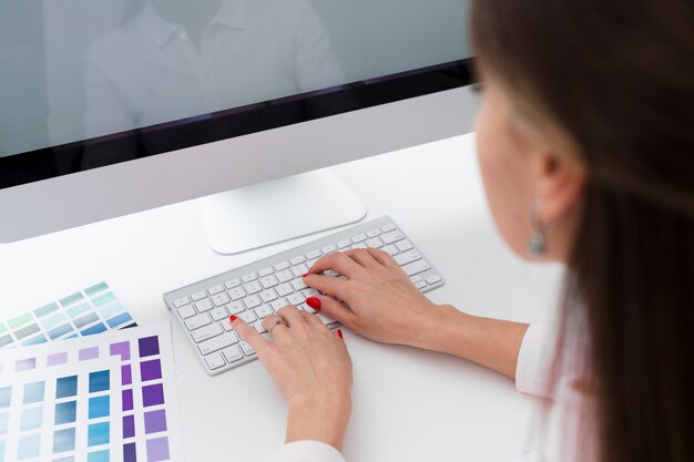 Hoher Winkel der Frau schreibend auf dem Computer bei der Arbeit