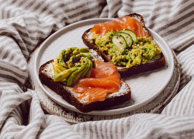 Hoher Winkel der Frühstücksbrötchen auf dem Bett mit Lachs und Avocado