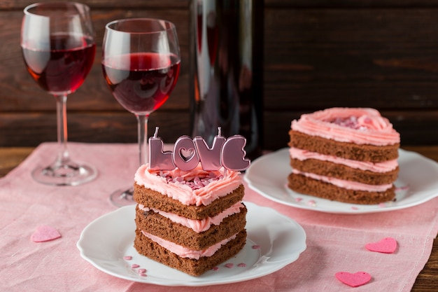 Hoher Winkel der herzförmigen Kuchenscheiben mit Weingläsern