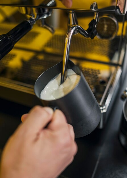 Hoher Winkel der männlichen Barista-Milchschaum