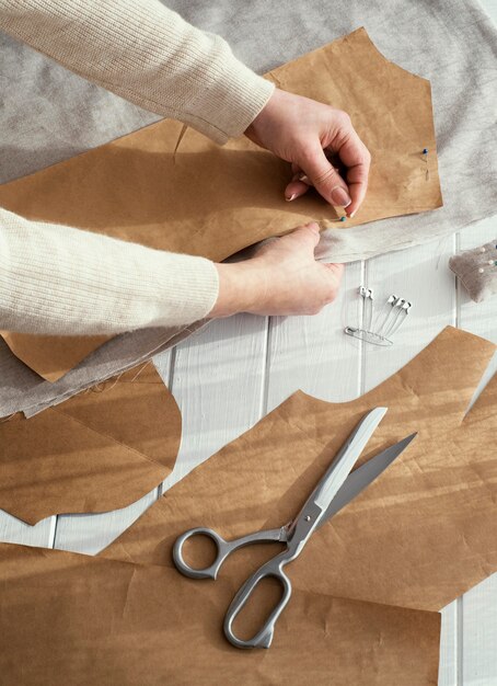 Hoher Winkel der Näherin mit Stoffen und Scheren