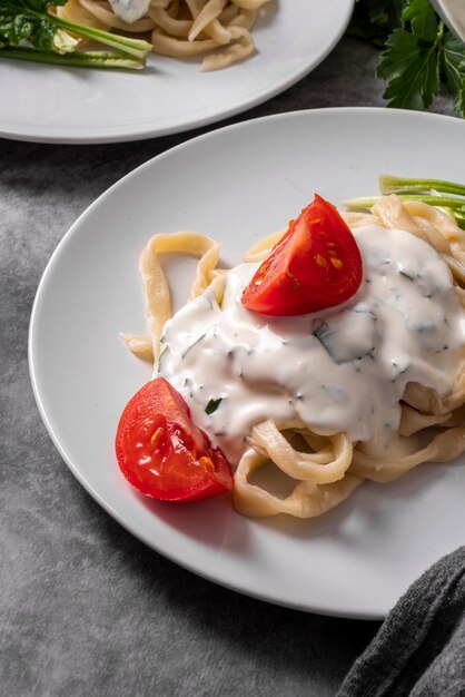 Hoher Winkel der Nudelschale mit Dressing und Tomaten