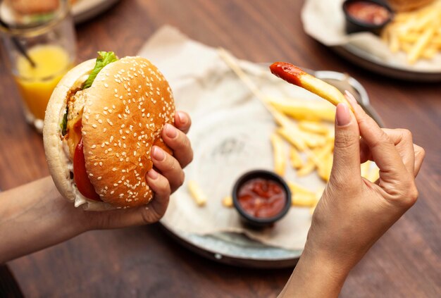 Hoher Winkel der Person, die Burger und Pommes frites isst