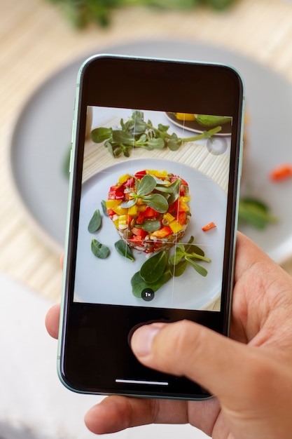 Hoher Winkel der Person, die Essen auf dem Teller mit Smartphone fotografiert