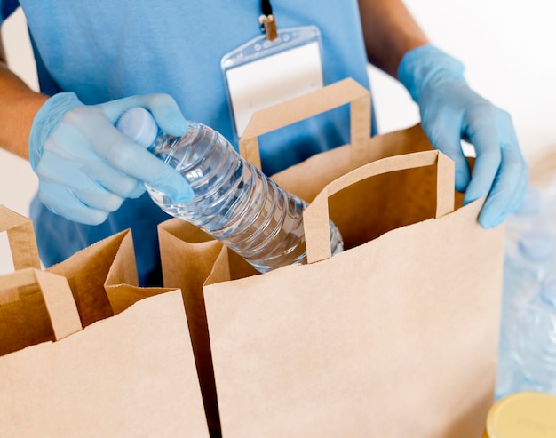 Hoher Winkel der Person, die Wasser in Spendenbeutel legt