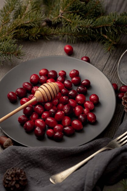 Hoher Winkel der Platte mit Moosbeeren und Honigschöpflöffel