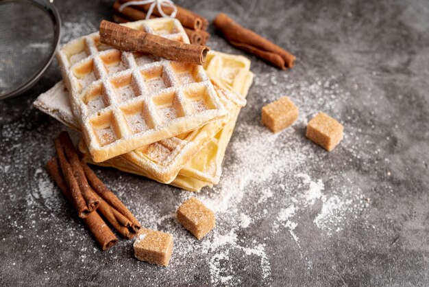 Hoher Winkel der Waffeln gestapelt mit Zimtsteuerknüppeln und Zuckerwürfeln