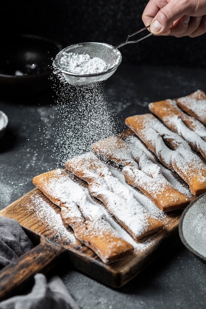 Hoher Winkel des Handsiebens von Puderzucker auf Desserts