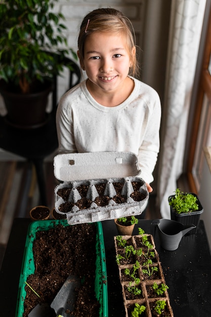 Kostenloses Foto hoher winkel des kleinen mädchens, das gepflanzte samen im eierkarton hält