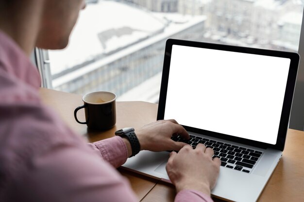 Hoher Winkel des Mannes, der im Büro mit Laptop arbeitet