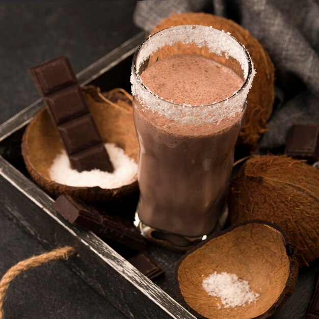 Hoher Winkel des Milchshake-Glases auf Tablett mit Kokosnuss und Schokolade