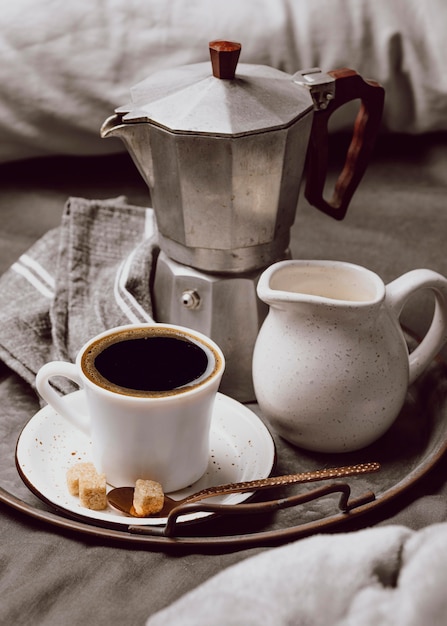 Hoher Winkel des Morgenkaffees auf dem Bett mit Milch und Wasserkocher