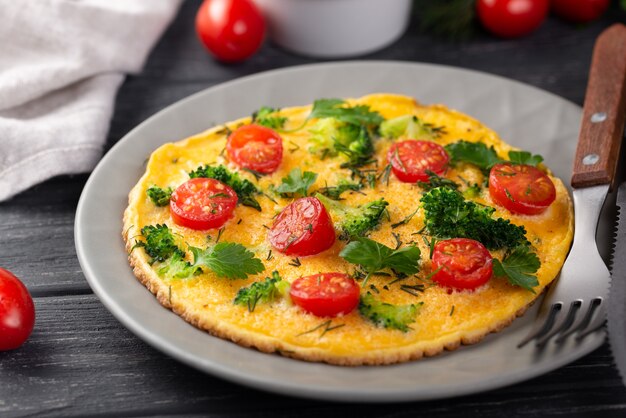 Hoher Winkel des Omeletts zum Frühstück mit Tomaten und Kräutern