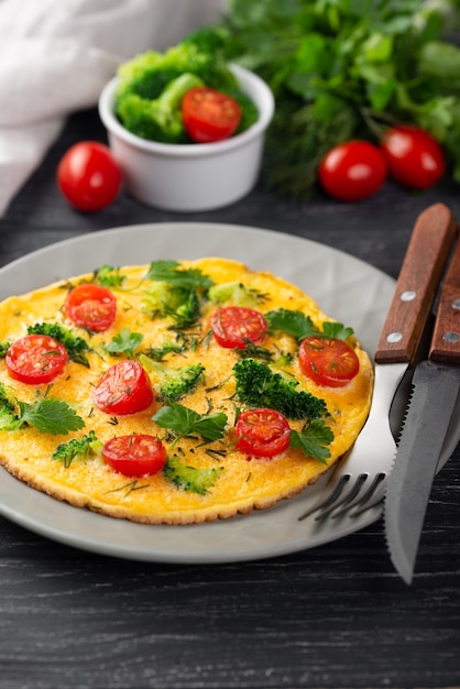 Hoher Winkel des Omeletts zum Frühstück mit Tomaten und Tischbesteck