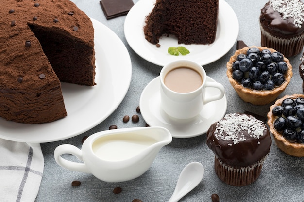 Hoher Winkel des Schokoladenkuchens mit Blaubeertörtchen und Kaffee