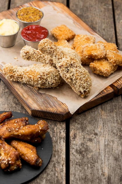 Kostenloses Foto hoher winkel von gebratenem huhn mit drei verschiedenen saucen und nuggets