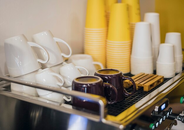 Hoher Winkel von Kaffeemaschine und Tassen