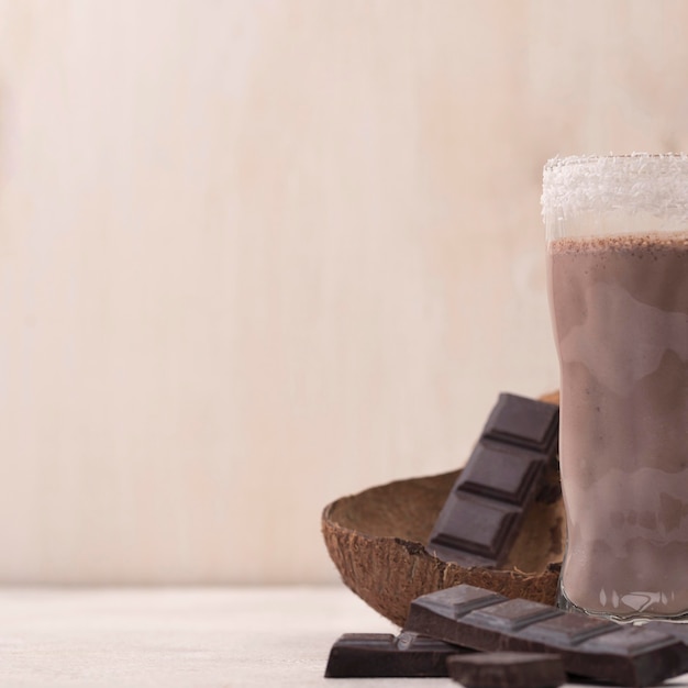 Hoher Winkel von Schokoladenmilchshake-Glas mit Kopierraum und Kokosnuss