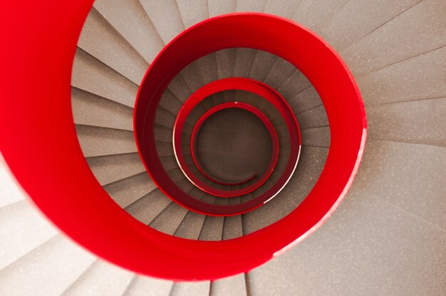 Hoher Winkelschuss einer Wendeltreppe mit einem roten Geländer