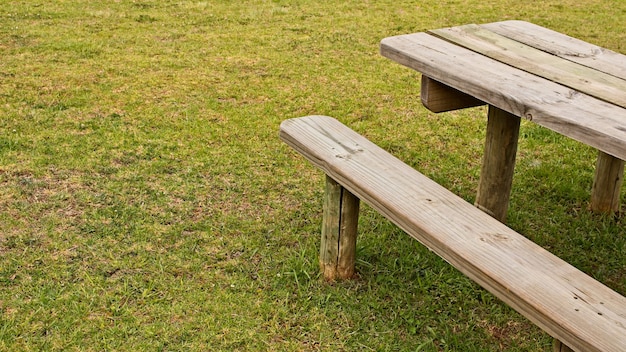 Hoher Winkelschuss eines Holztischs und einer Bank auf dem grasbedeckten Feld