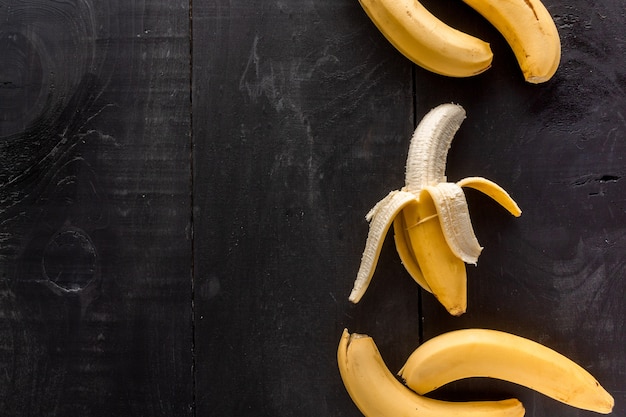 Kostenloses Foto hoher winkelschuss von bananen mit einem kopienraum auf einem schwarzen hintergrund