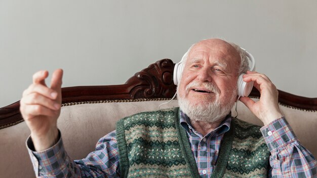 Hoher Winkelsenior auf hörender Musik der Couch