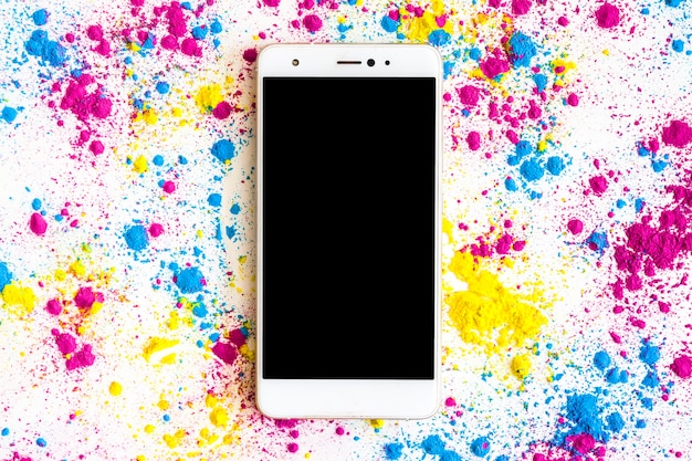 Kostenloses Foto holi-farbpulver um das smartphone mit schwarzer bildschirmanzeige