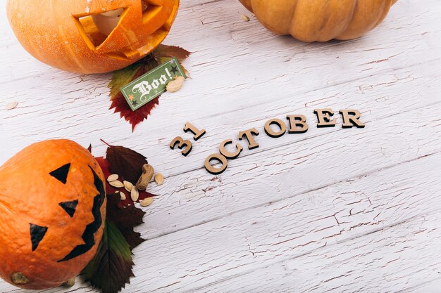 Holz Schriftzug &#39;31 Oktober &#39;liegt vor großen Halloweenkopf Hallowein Kürbisse auf weißen Tisch