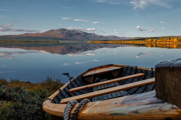 Holzboot am Ufer eines großen schönen ruhigen Sees