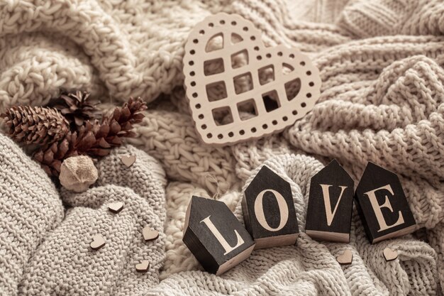 Holzbuchstaben bilden das Wort Liebe über kuscheligen Strickwaren. Valentinstag Urlaubskonzept.