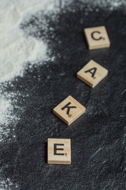 Holzbuchstaben wie Kuchen auf Schwarz geschrieben.