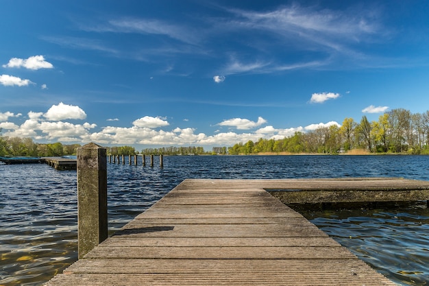 Holzdock auf dem Meer unter dem Sonnenlicht und einem blauen bewölkten Himmel