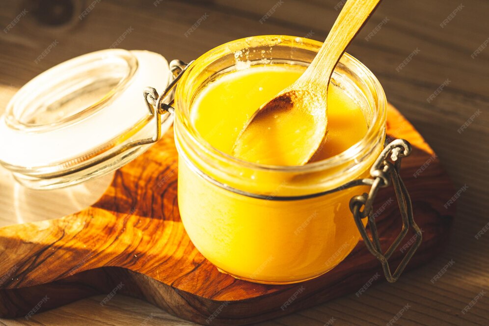 Holzlöffel mit ghee butterschmalz im glasgefäß in der