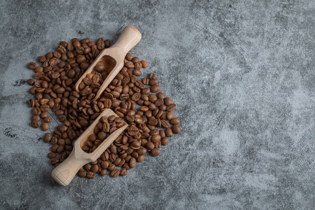 Holzlöffel mit Kaffeebohnen auf grauem Hintergrund.