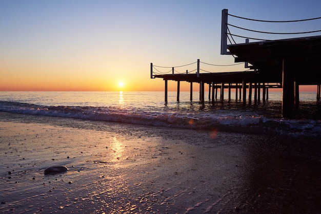 Holzpier auf einem ausgefallenen orange Sonnenuntergang.