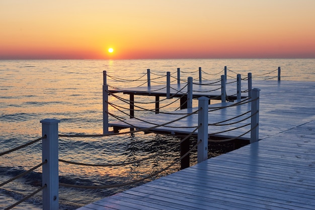 Holzpier auf einem ausgefallenen orange Sonnenuntergang.