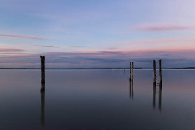 Holzpier, der das Meer unter dem schönen Sonnenunterganghimmel reflektiert