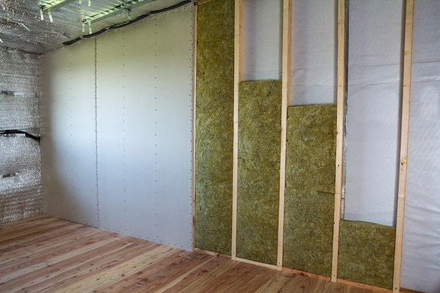 Holzrahmen für zukünftige wände mit trockenbauplatten, die mit steinwolle und glasfaserisolierpersonal für die kältesperre isoliert sind. komfortables warmes haus, wirtschaftlichkeit, bau- und renovierungskonzept.