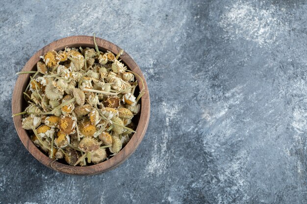 Holzschale getrocknete Kamille auf Marmortisch.