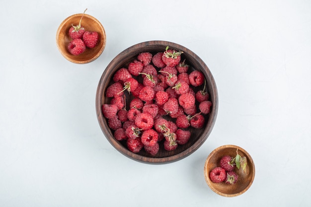 Holzschale mit gesunden leckeren Himbeeren auf Steinoberfläche