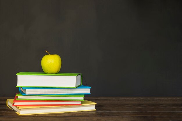 Holzschreibtisch mit Büchern und Apfel